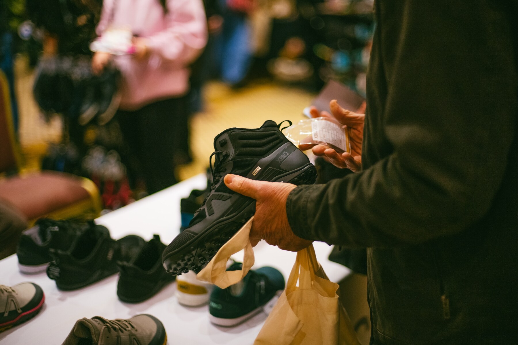 A visitor examining a black barefoot shoe at an exhibitor stand, photo by The Foot Collective