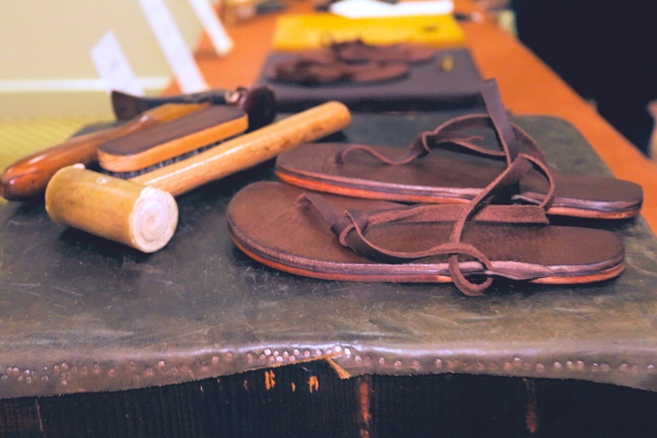 Leather shoes and a wooden mallet displayed on an exhibitor table, photo by The Foot Collective