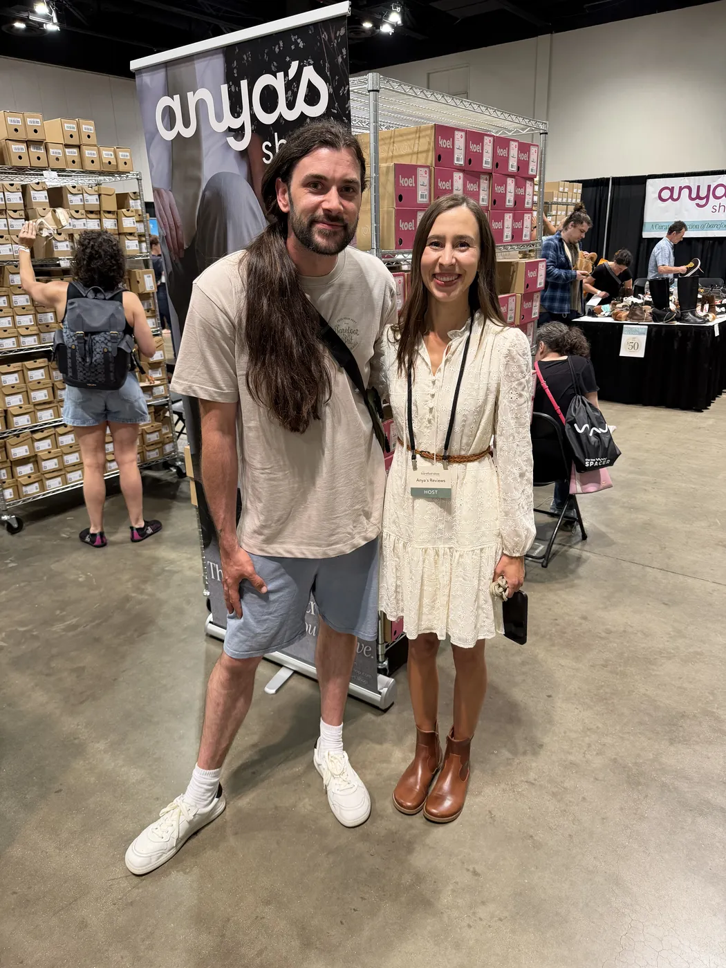 Dan with Anya at her barefoot shoe event, in front of stacks of shoe boxes
